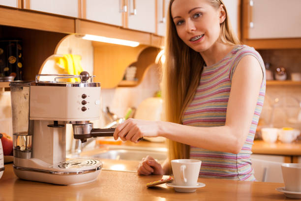 istock Woman in kitchen making coffee from machine 1360658545