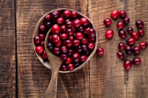 istock Red cranberries on wooden background. Brries in a bowl. 1360658572