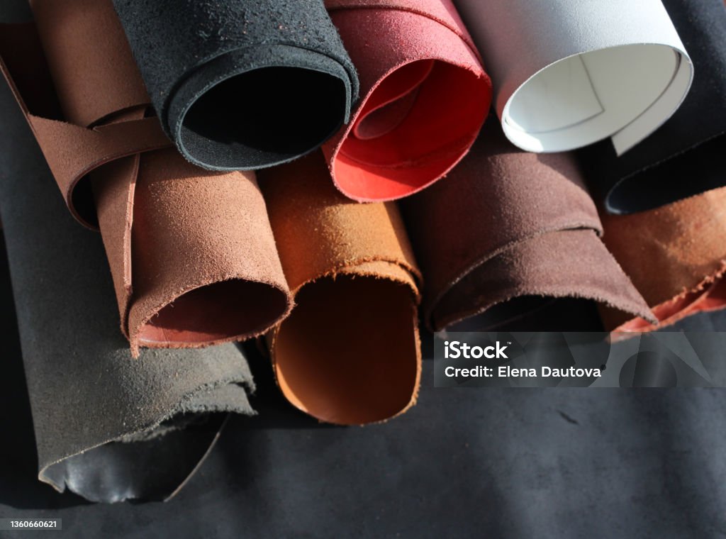 Close-up pieces of the leather material on the working desk in the leather workshop. Leather Stock Photo