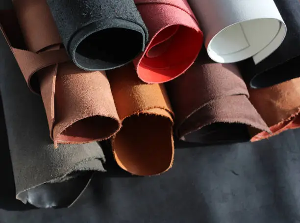 Photo of Close-up pieces of the leather material on the working desk in the leather workshop.