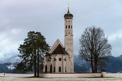 church st. coloman in winter landscape with mountains in the background