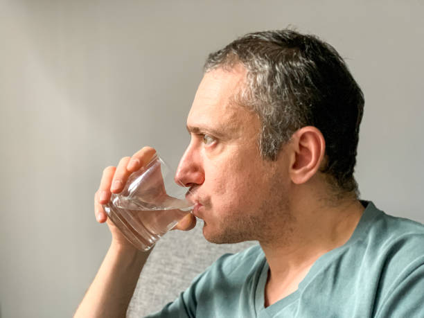 istock Man is drinking water from glass 1360662614