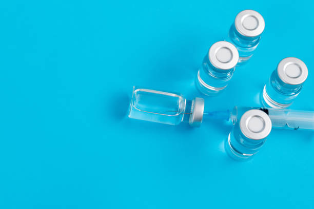 syringe inserted into the vial on blue background - syringe vaccination vial insulin imagens e fotografias de stock
