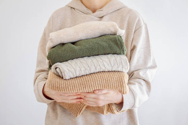 istock Woman's hand holding a stack of clothes. Clothes Donation, Renewable Concept.Preparing Garment at Home before Donate 1360667636