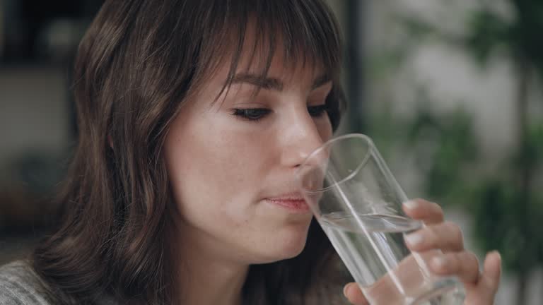 Woman with vitiligo taking painkiller pill, drinking glass of water, healthcare