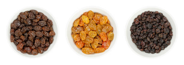 Commercial raisins, golden raisins and small Zante currants in white bowls Common commercial raisins, golden raisins (Sultanas), and small currants (Zante currants or Black Corinth), in white bowls. Dried seedless grapes, to be eaten raw or used in cooking and baking. Photo. RAISINS stock pictures, royalty-free photos & images