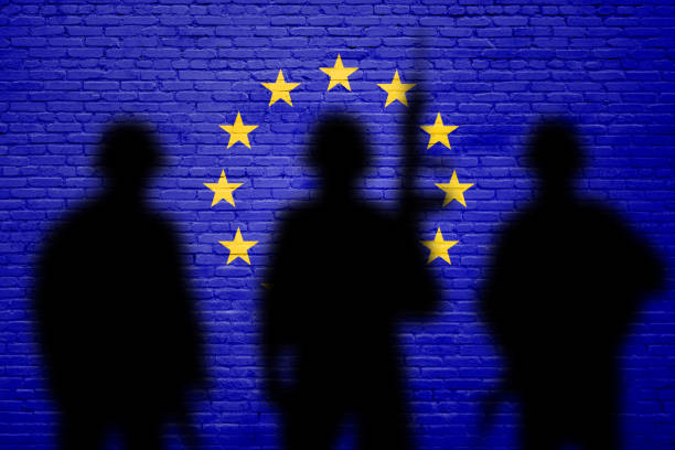 Flag of Europe Union painted on a brick wall with soldiers shadows. War concept stock photo