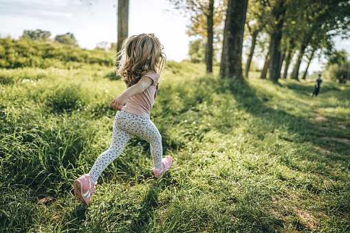 Little girl running on grass field on sunny day