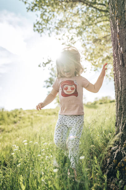 istock Cute smiling girl walking on grass field and laughing 1360675065