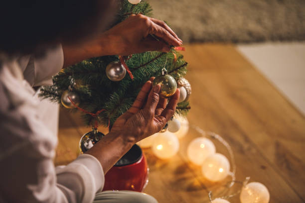 istock Hanging an ornament on a branch of a small Christmas tree 1360675103
