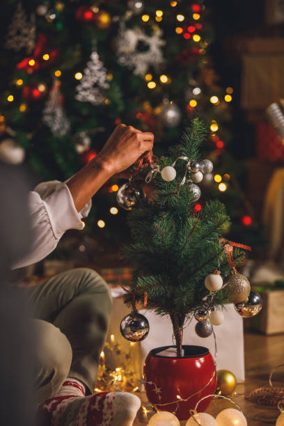 istock Woman hanging ornaments on a small Christmas tree 1360675104