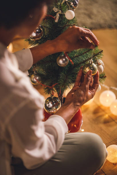 istock Woman hanging ornaments on a small Christmas tree 1360675108