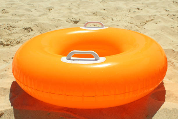 istock Orange children's circle for swimming on a sandy beach. Close-up. 1360675191