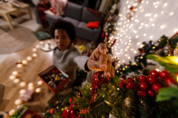 istock Woman hanging a glittery red Christmas ornament on a Christmas tree 1360675475