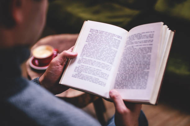 istock Man reading book and drinking coffee in the living room 1360676699