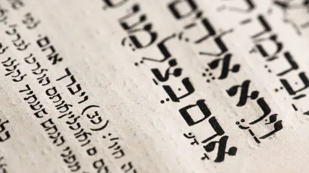 Closeup of hebrew word in Torah page that translates in english as Adam, Biblical figure. First man in the Garden of Eden. Selective focus