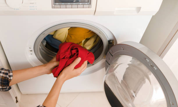 istock Woman puts bright clothes into a washing machine. 1360678928