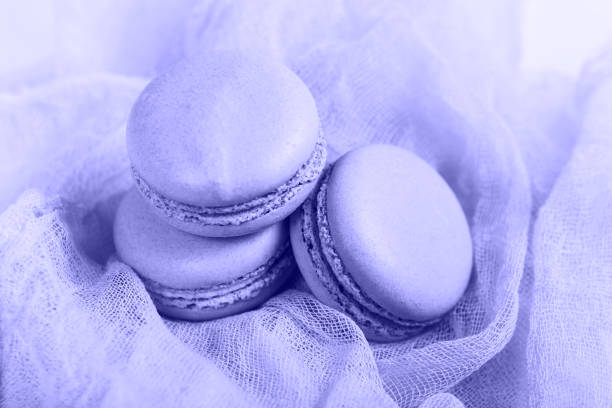 Delicious Purple Very Peri french dessert. Three gentle soft pink cakes  macaron or macaroon on airy fabric stock photo