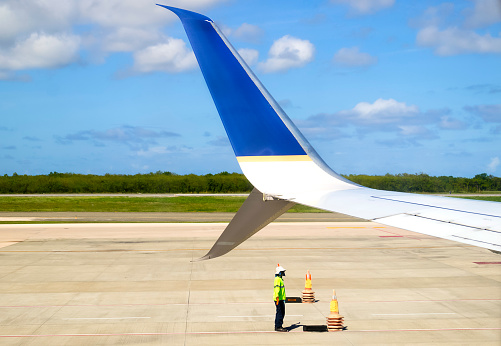 worker on the airport ground and airplane winglet detail at Punta Cana International airport, Punta Cana, Dominican Republic, November 18, 2021