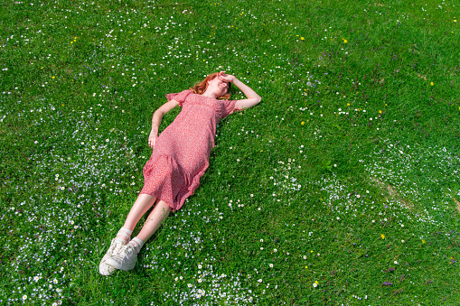 ender beautiful woman in rose dress lay on a spring grass, sunny meadow, cheerful candid people
