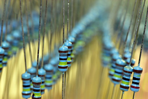 Artistically arranged new resistors of the same rating with a power of 0.25 watts in their original packaging. The picture was taken with a shallow depth of field.