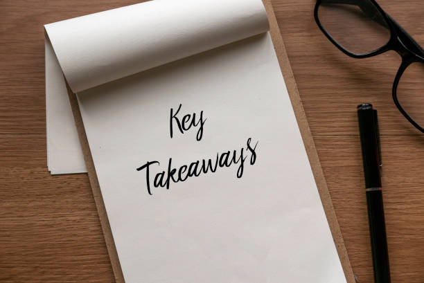 Pen, glasses and clipboard with a paper written with Key Takeaways. stock photo