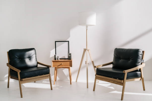 istock Leather armchairs standing near side table and lamp in office 1360684984
