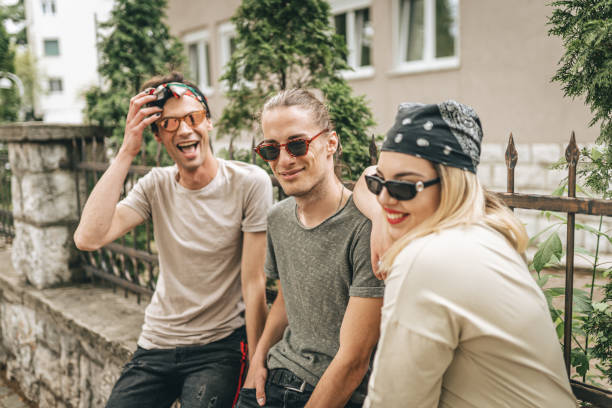 istock Three friends sitting on fence and posing 1360689055
