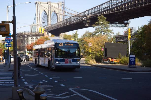 Passenger bus under Brooklyn Bridge Brooklyn, NY, USA - Dec 24, 2021: The route B25 bus in Brooklyn heading east on Old Fulton St below the Brooklyn Bridge warren street brooklyn stock pictures, royalty-free photos & images