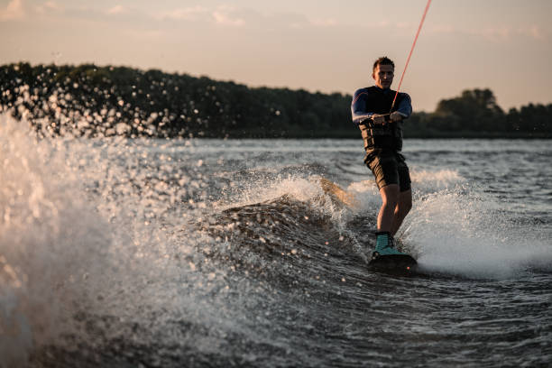istock view of strong man holding rope and rides down the wave on wakeboard 1360691012