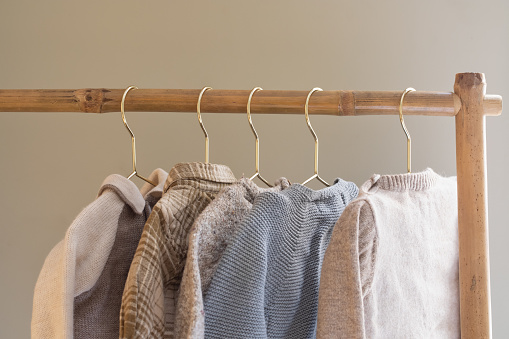 Baby clothes collection hanging on a wooden clothing rack on golden clothes hangers