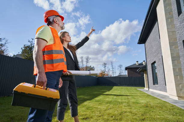 istock Female engineer pointing at house to worker with toolkit 1360691262