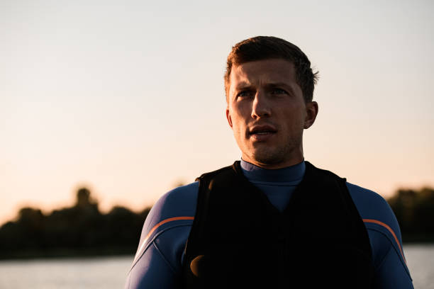portrait of young attractive athletic man in wetsuit and vest portrait of young attractive athletic man in wetsuit and vest against the background of the sky soaked suit stock pictures, royalty-free photos & images