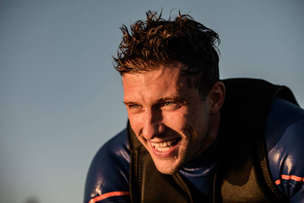 portrait of young cheerful athletic man in wetsuit and vest portrait of young cheerful athletic man in wetsuit and vest against the background of the sky soaked suit stock pictures, royalty-free photos & images