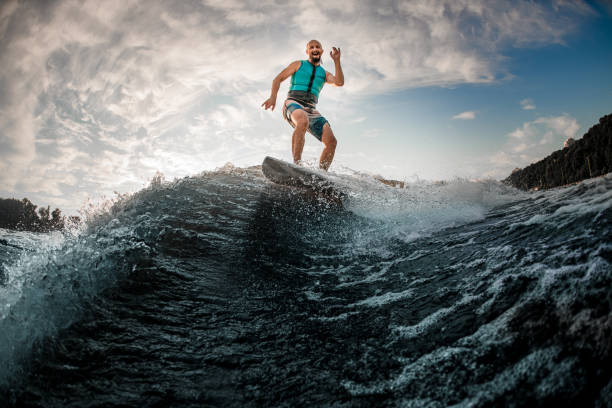 istock cheerful man wakesurfer having fun and balancing on wakeboard along the river wave 1360693020