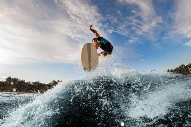 istock energy male wakeboarder performs trick in jump using high waves by the river 1360694214