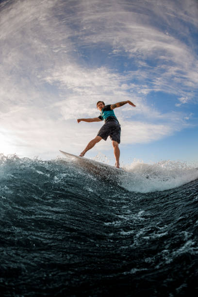 istock active man wakesurfer balancing on board on splashing river wave against blue sky 1360694325