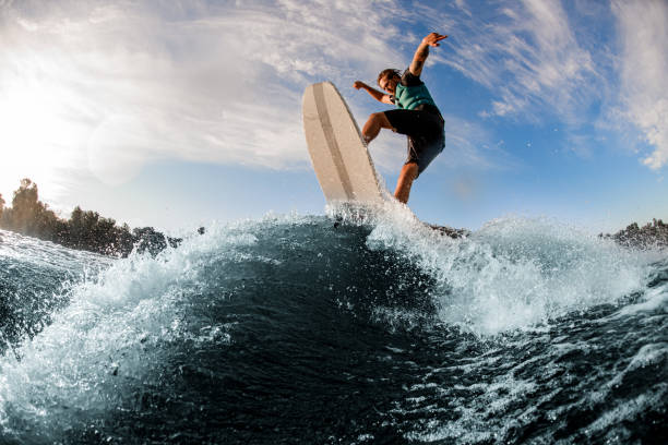 istock young sportive man having fun and jumping up on wakesurf board on river wave 1360695082