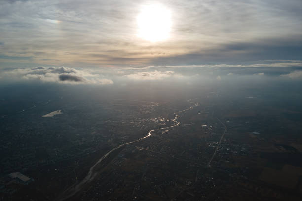 vue aérienne depuis la fenêtre de l’avion à haute altitude d’une ville lointaine recouverte d’une couche de smog brumeux mince et de nuages lointains le soir - ozone layer photos et images de collection