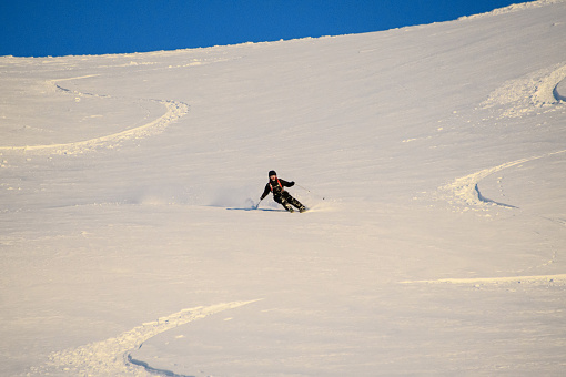 Teenage boy skiing on a long, narrow lane at ski resort in the Alps. \nSunny winter day.\nShot with Canon R5.