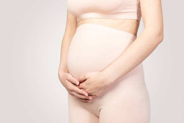 istock Pregnant women holding hands on abdomen side view studio shot 1360697346