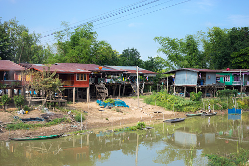 Old simple thai houses on stilts in Kong Krai Lat in Sukhothai province at fishing lake / river.  Houses are homes of fishing people  in old fishing town. Buildings are weathered and old
