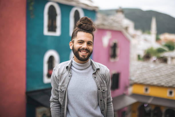 istock Young man with beard posing on city street 1360700544