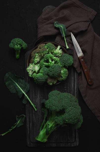 istock Fresh broccoli, on a cutting board, black background, top view, no people, vertical, 1360704095