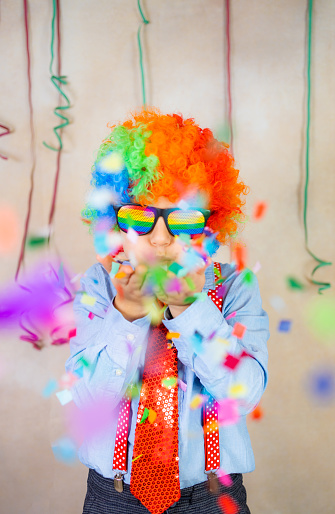 Funny boy blowing confetti at carnival