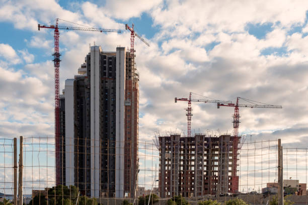 istock Two skyscrapers under construction with four red cranes. 1360706467