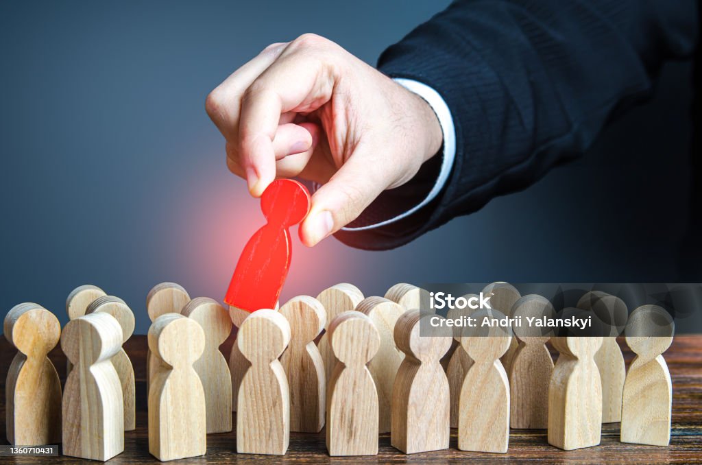 Hand pulls red man out of group. Dismissal, weak link. Identify the culprit among the suspects. Identify the infected person. Zero patient of new strain. Identifying intruder. Collective immunity. Out Of Service Stock Photo