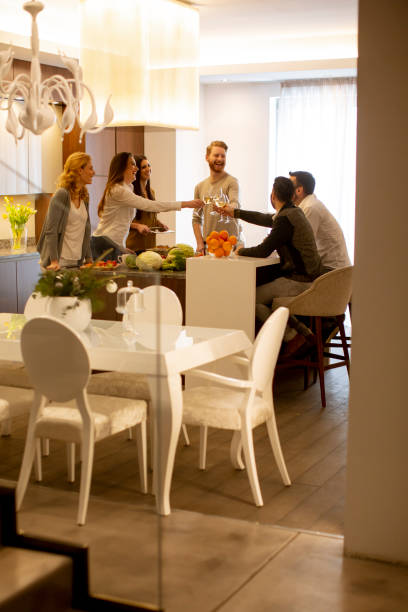 istock Group of young people preparing meal, drinking white wine and having a good time 1360711943