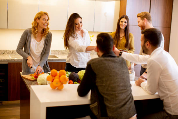 istock Group of young people preparing meal, drinking white wine and having a good time 1360711946