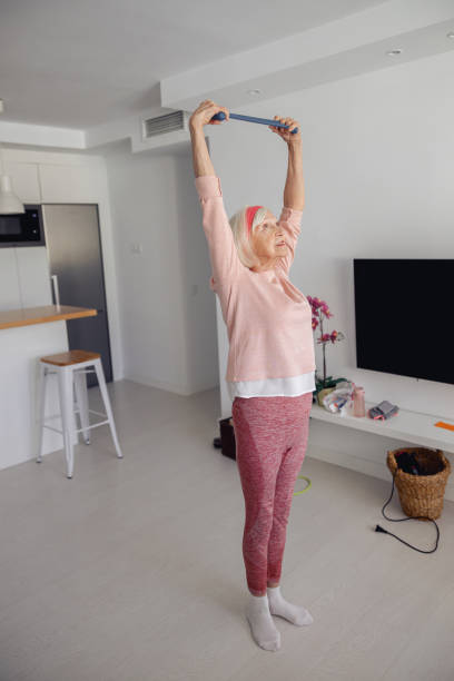 istock Senior lady improving her flexibility with elastic strap indoors 1360712715